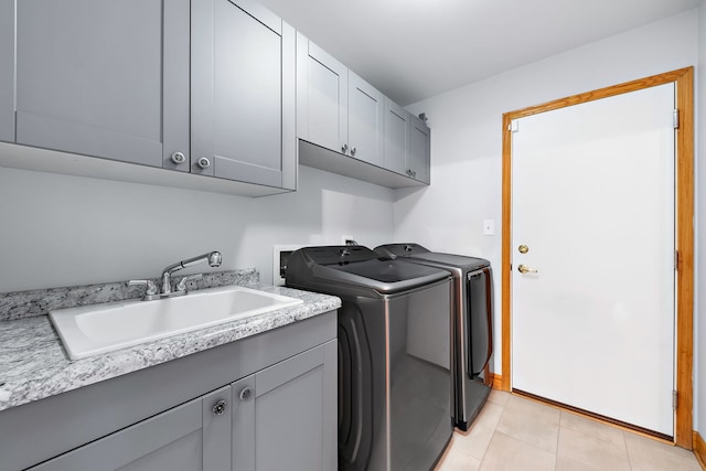 clothes washing area featuring cabinets, light tile patterned floors, washing machine and clothes dryer, and sink