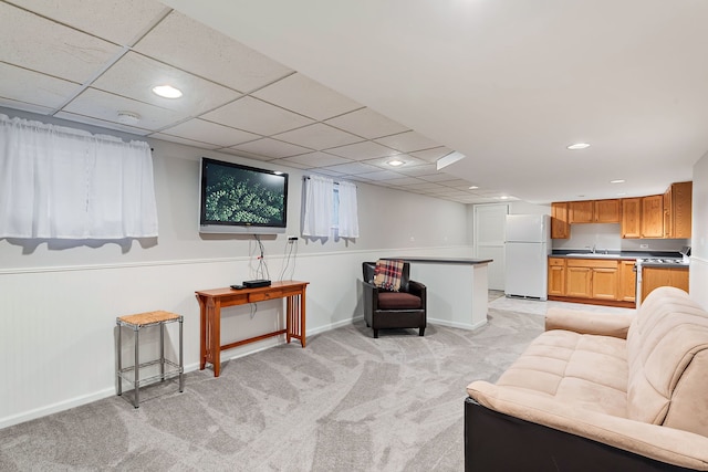 carpeted living room featuring sink and a drop ceiling