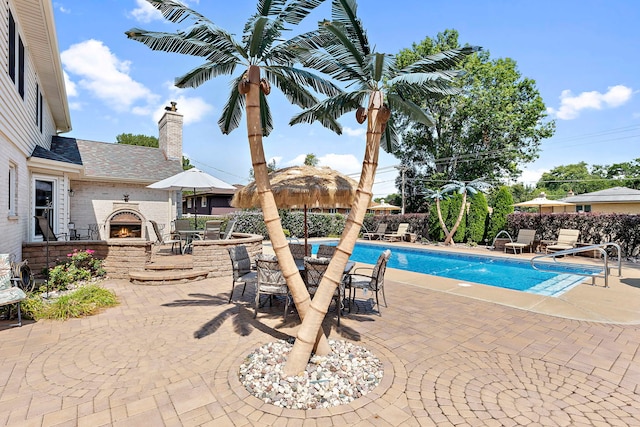 view of pool featuring an outdoor fireplace and a patio