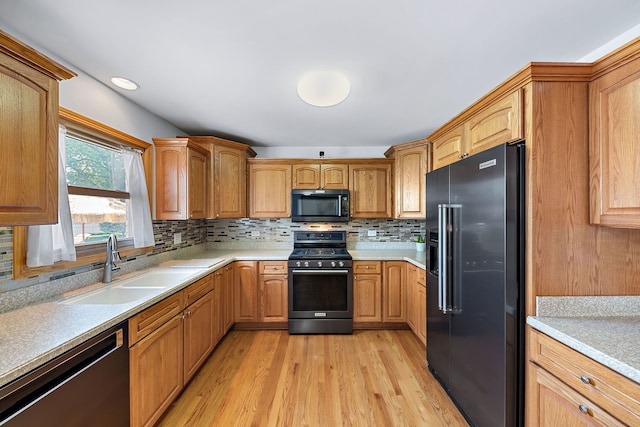 kitchen featuring decorative backsplash, sink, black appliances, and light hardwood / wood-style flooring