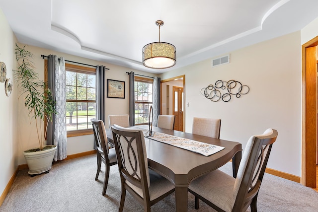 carpeted dining space featuring a tray ceiling