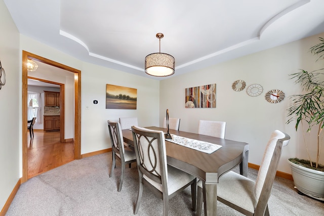 dining room featuring carpet and a tray ceiling