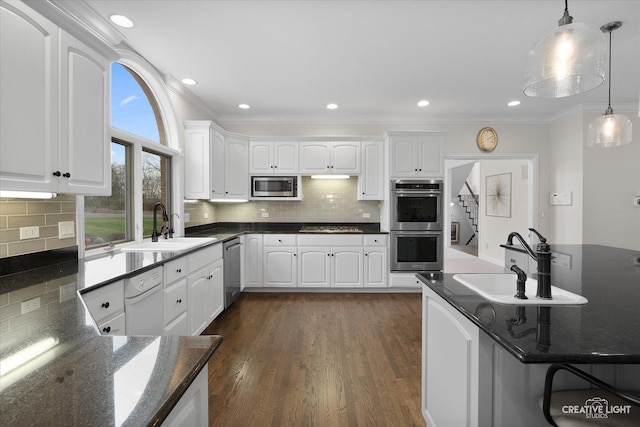 kitchen featuring decorative light fixtures, stainless steel appliances, white cabinetry, ornamental molding, and sink