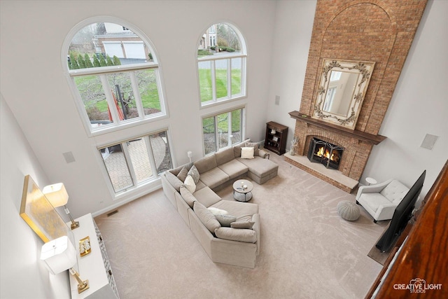 living room with a brick fireplace, a towering ceiling, and carpet floors