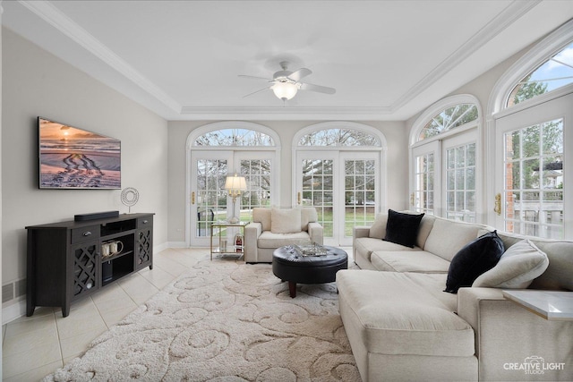 living room with a raised ceiling, crown molding, light tile patterned floors, ceiling fan, and french doors