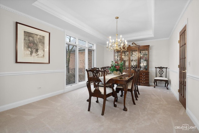 dining space featuring a raised ceiling, ornamental molding, a notable chandelier, and light colored carpet