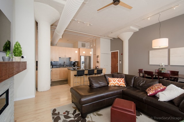 living room featuring rail lighting, light hardwood / wood-style floors, ceiling fan, and sink