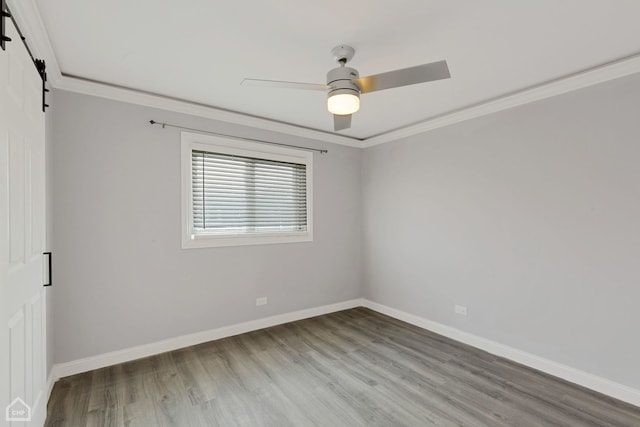 spare room with hardwood / wood-style floors, ceiling fan, a barn door, and crown molding