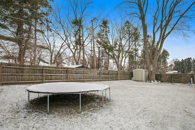 snowy yard with a trampoline and a storage shed