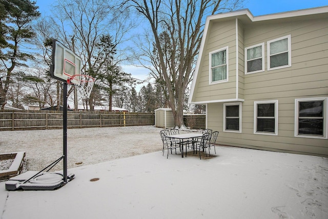 snow covered patio featuring a storage shed