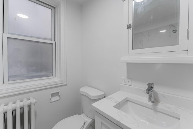 bathroom featuring a shower, radiator heating unit, vanity, and toilet