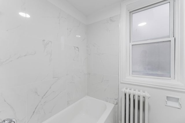 bathroom featuring radiator and a bathtub