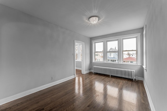 empty room with dark hardwood / wood-style flooring and radiator