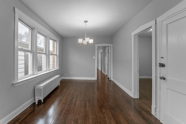 unfurnished dining area featuring dark hardwood / wood-style flooring, radiator heating unit, and an inviting chandelier