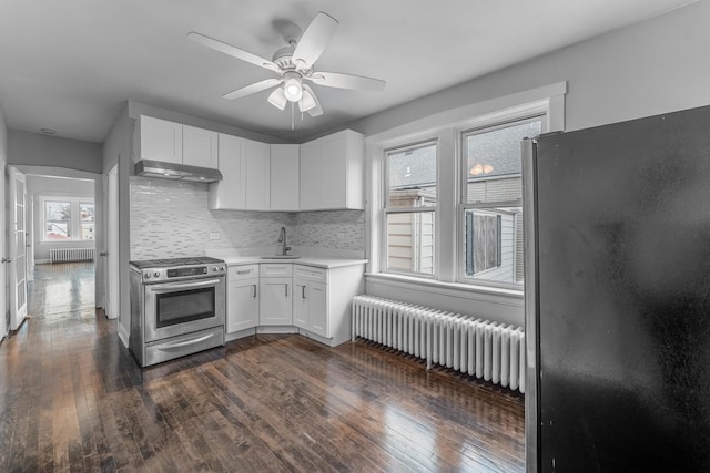 kitchen featuring decorative backsplash, white cabinetry, radiator heating unit, and appliances with stainless steel finishes