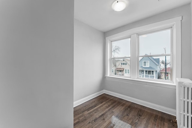 empty room featuring dark hardwood / wood-style flooring and radiator heating unit