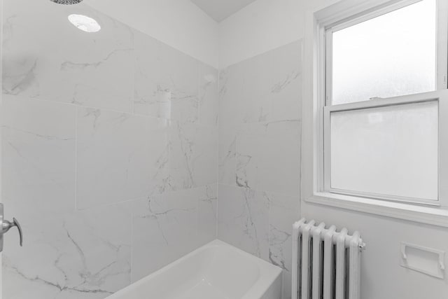 bathroom featuring radiator heating unit and tiled shower / bath combo