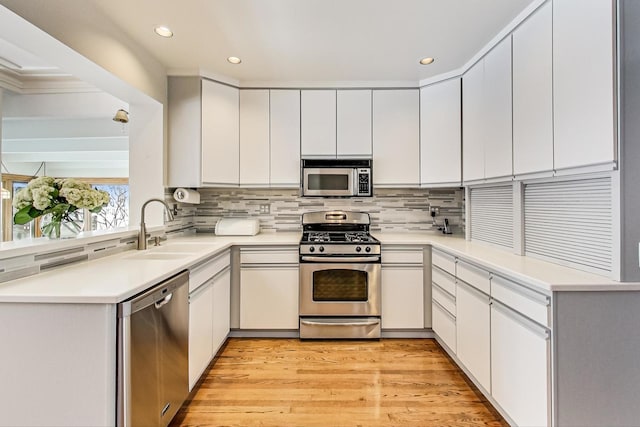 kitchen featuring sink, stainless steel appliances, white cabinetry, and light hardwood / wood-style floors