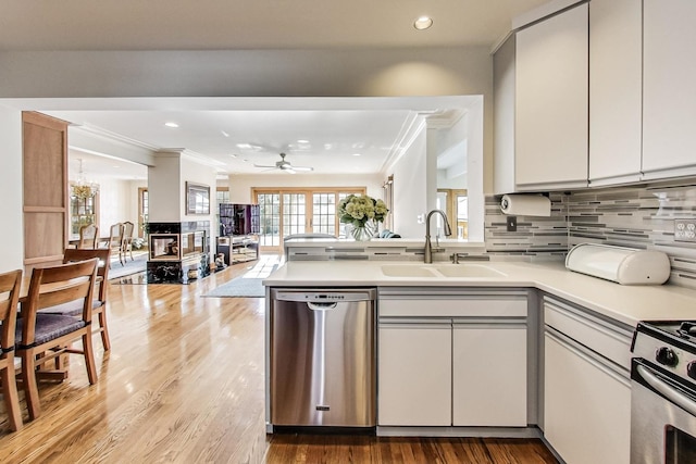 kitchen with kitchen peninsula, stainless steel appliances, white cabinetry, ceiling fan, and sink