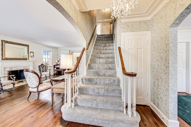 staircase with hardwood / wood-style flooring, an inviting chandelier, and ornamental molding