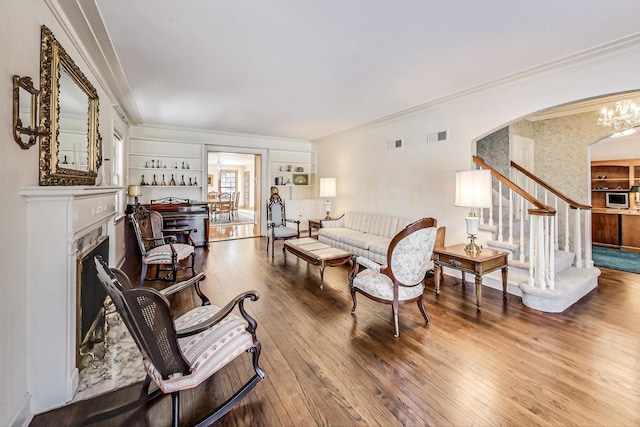 living room featuring a chandelier, hardwood / wood-style floors, built in shelves, and ornamental molding