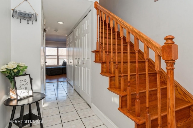 stairway with crown molding and tile patterned flooring