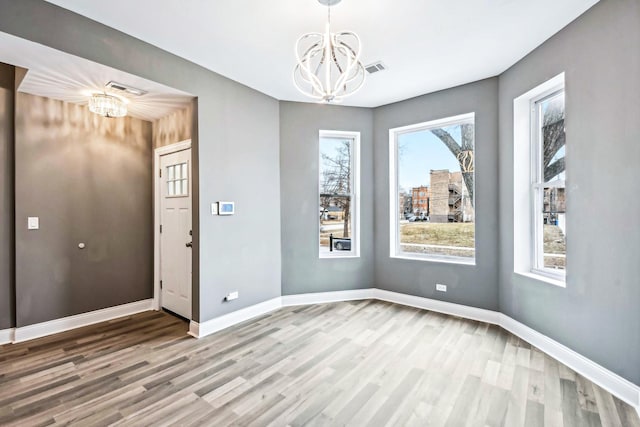 spare room featuring wood-type flooring and an inviting chandelier