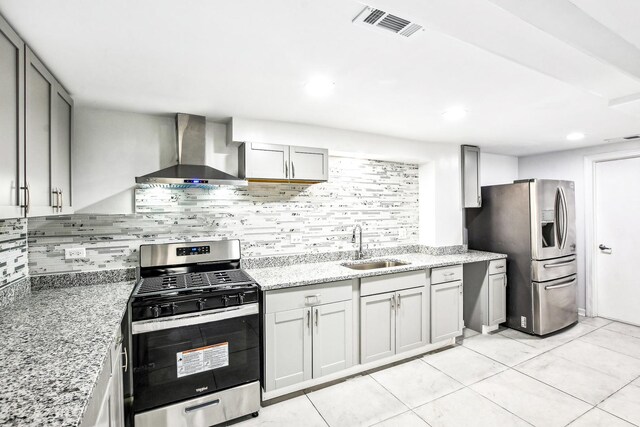 kitchen with light stone counters, gray cabinetry, stainless steel appliances, sink, and wall chimney range hood