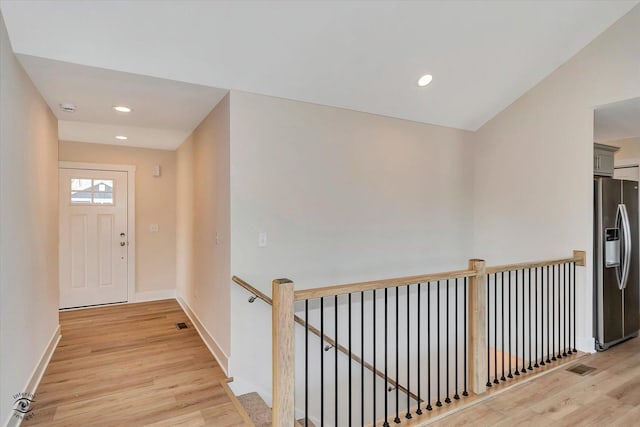 corridor featuring vaulted ceiling and light hardwood / wood-style flooring