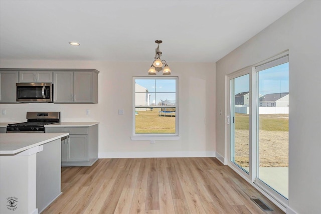 kitchen with light hardwood / wood-style floors, stainless steel appliances, pendant lighting, a chandelier, and gray cabinets