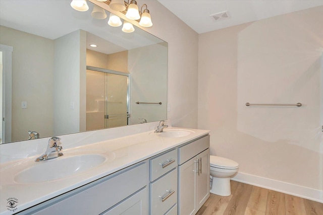 bathroom with hardwood / wood-style flooring, vanity, a shower with shower door, and toilet