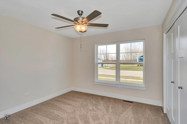 spare room featuring ceiling fan, plenty of natural light, and carpet