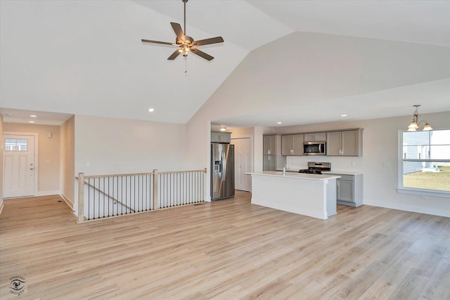 unfurnished living room with ceiling fan with notable chandelier, light hardwood / wood-style floors, high vaulted ceiling, and sink