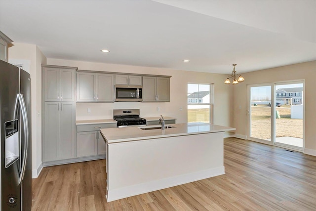 kitchen with a chandelier, a center island with sink, pendant lighting, and appliances with stainless steel finishes