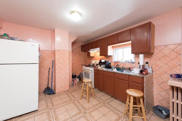 kitchen featuring a textured ceiling, white appliances, and sink