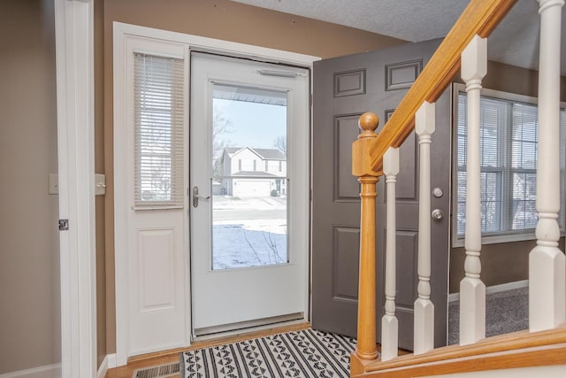 entryway with a textured ceiling, hardwood / wood-style flooring, and a healthy amount of sunlight