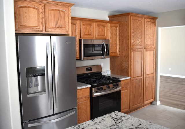 kitchen with light stone countertops, stainless steel appliances, and light tile patterned floors