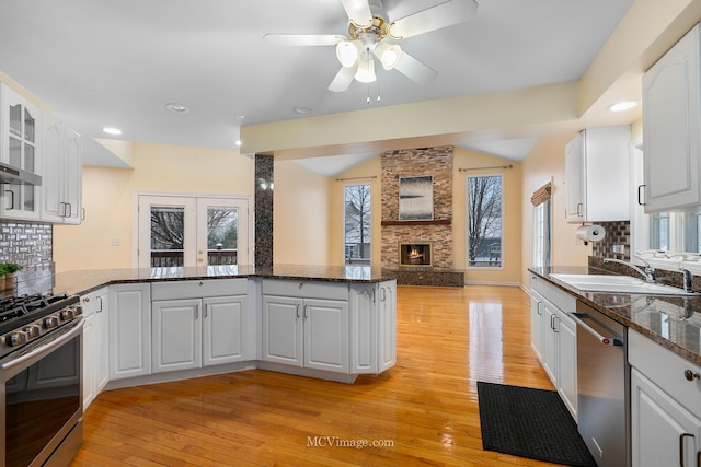 kitchen with kitchen peninsula, appliances with stainless steel finishes, ceiling fan, sink, and white cabinetry