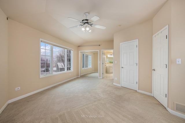 unfurnished bedroom with connected bathroom, light colored carpet, vaulted ceiling, and ceiling fan