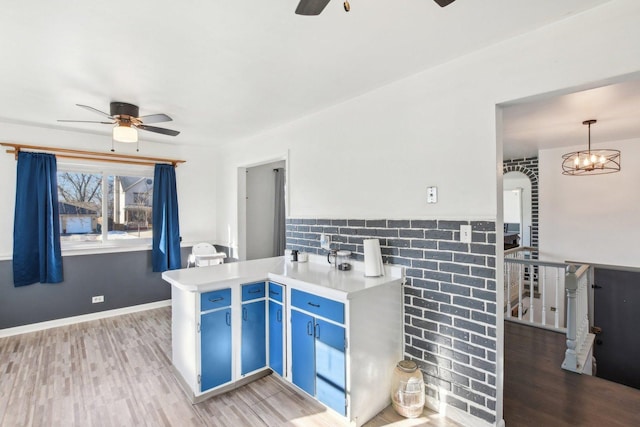 kitchen with hardwood / wood-style flooring, ceiling fan, blue cabinets, and hanging light fixtures