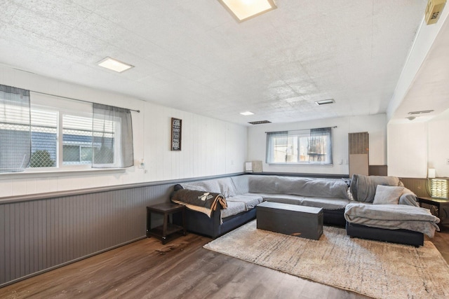 living room featuring hardwood / wood-style floors, a textured ceiling, a healthy amount of sunlight, and wood walls