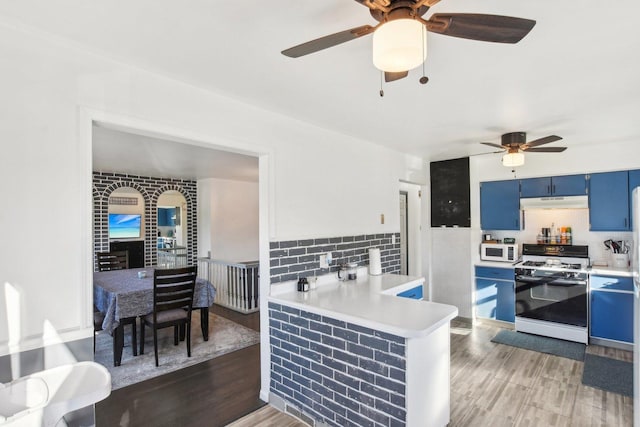 kitchen featuring white appliances, hardwood / wood-style flooring, blue cabinetry, ceiling fan, and kitchen peninsula