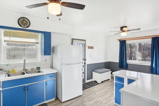 kitchen featuring white refrigerator, sink, and blue cabinets