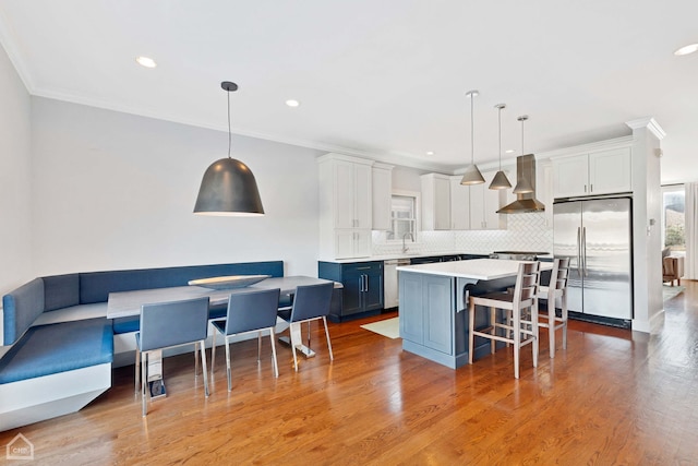 kitchen featuring extractor fan, pendant lighting, white cabinetry, stainless steel appliances, and blue cabinetry