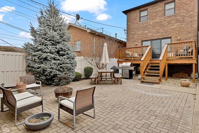 view of patio / terrace featuring grilling area, a deck, and a fire pit