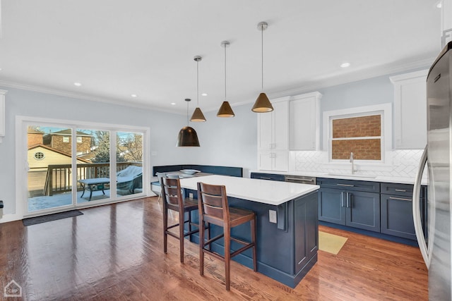 kitchen with sink, white cabinets, hanging light fixtures, a center island, and blue cabinetry