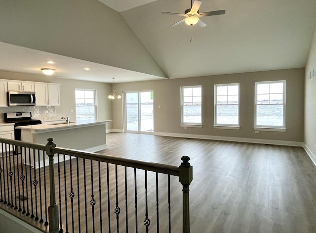 living room with ceiling fan with notable chandelier, light hardwood / wood-style flooring, lofted ceiling, and sink