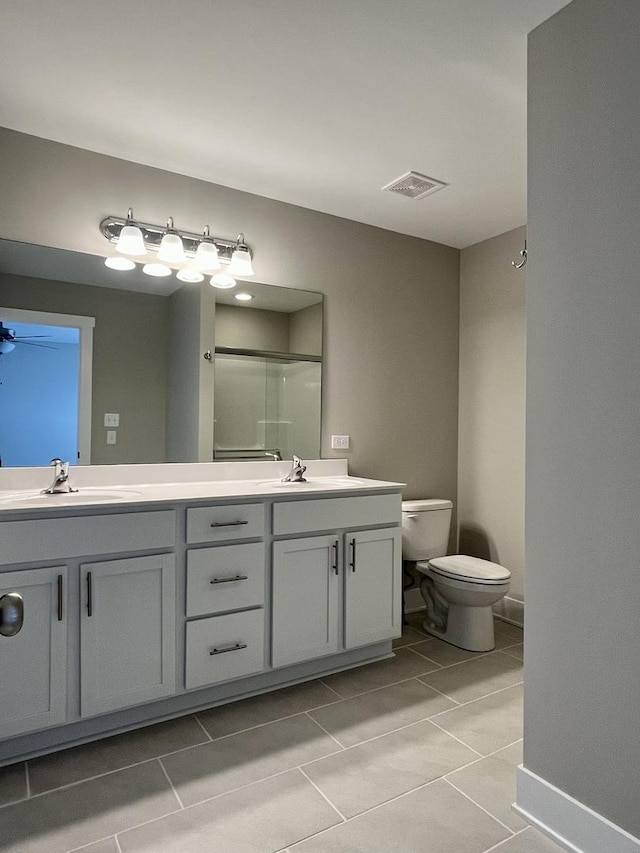 bathroom with tile patterned floors, vanity, a shower with shower door, and toilet