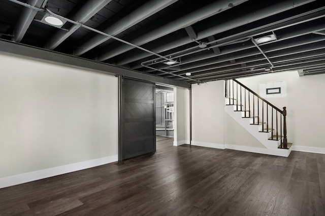 basement featuring a barn door and dark hardwood / wood-style floors