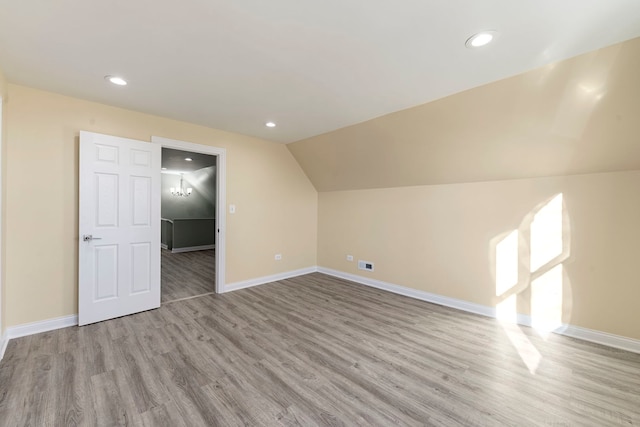 additional living space featuring light hardwood / wood-style flooring and vaulted ceiling